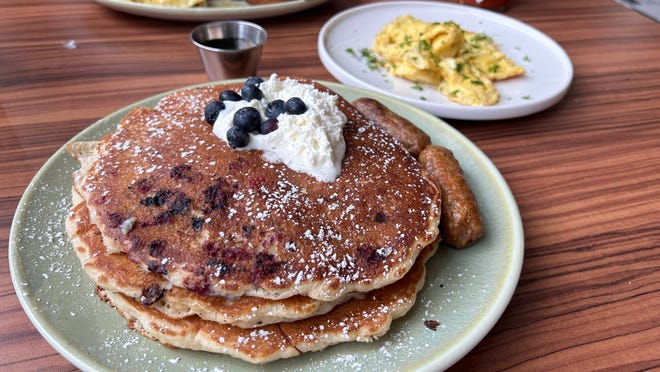 At Presley’s Kitchen and Bar, a plate of blueberry pancakes is elevated with housemade lemony whipped cream and a handful of fresh blueberries