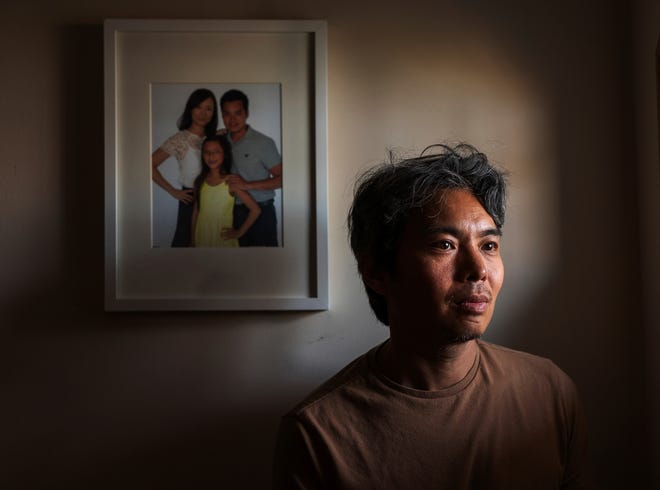 Jeff Wu, 47, of Lakeville, Minnesota stands by a photo of his family hanging in a hallway at his home on Thursday, December 7, 2023.