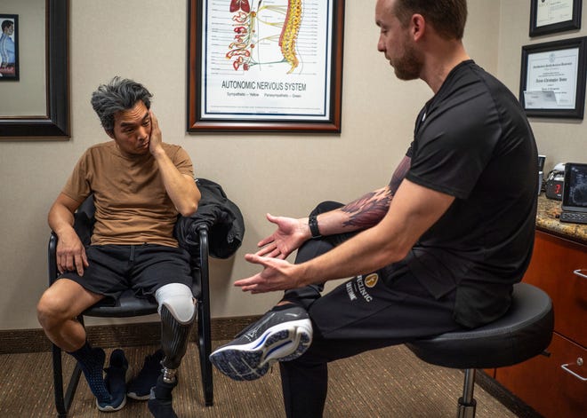 An exhausted Jeff Wu, 47, of Lakeville, listens to Dr. Aaron Howe go over plans after his visit with the chiropractor at Life Time Fitness in Lakeville, Minnesota on Thursday, December 7, 2023.