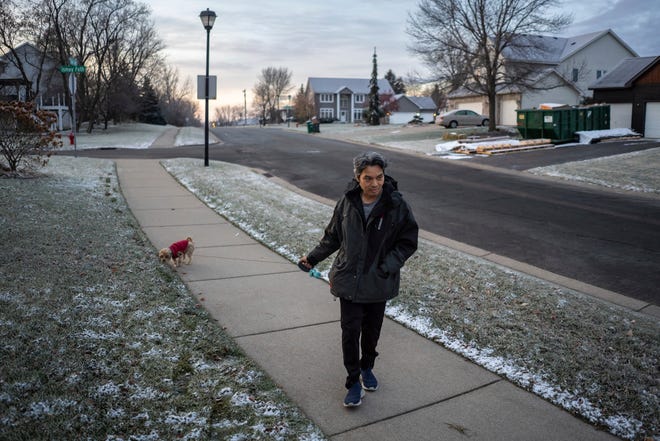 Jeff Wu, 47, of Lakeville, Minnesota takes his dog Willy for a walk in his neighborhood after arriving home in the early morning from his third shift job at a dairy factory on Wednesday, December 6, 2023.