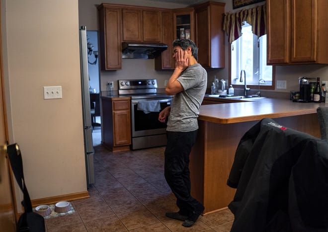 Jeff Wu, 47, of Lakeville, Minnesota shows signs of being tired while waiting for his dog to come and eat after arriving home from his third shift job at a dairy factory on Wednesday, December 6, 2023.