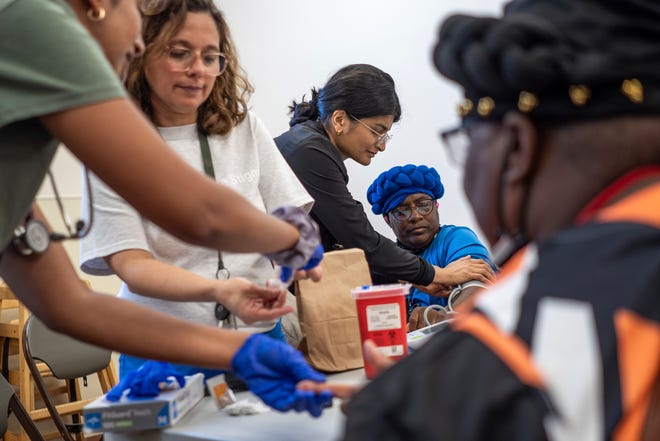 Community Health and Social Services family medicine physician Dr. Shaina Shetty, center, does a blood pressure check on Jackqueline Bowers, 51, of Detroit, while Michigan State University medical student Shalini Tummala, left, and CHASS family nurse practitioner Danny Diaz helps Jennifer Bowers, 51, of Detroit, during a stop to the Capuchin Soup Kitchen in Detroit while doing a street medicine outreach on Monday, August 12, 2024. CHASS recently received $562,868 in American Plan Act dollars to expand its street medicine team, to aid people experiencing homelessness on the streets taking medical care right to the people who need it.