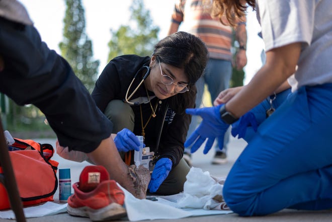 Community Health and Social Services family medicine physician Dr. Shaina Shetty helps tend to an open wound on the food of Daniel Lewis, 60, of Detroit, while doing street medicine outreach on Monday, August 12, 2024, at Manna Community Meals in Detroit's Corktown neighborhood. CHASS recently received $562,868 in American Plan Act dollars to expand its street medicine team, to aid people experiencing homelessness on the streets taking medical care right to the people who need it.